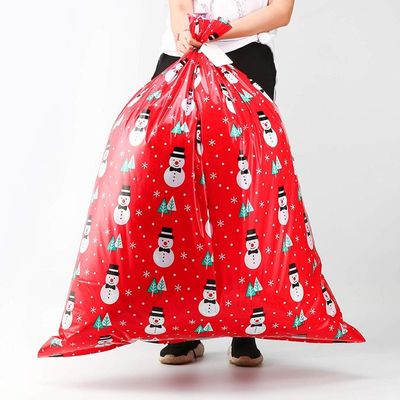 Il grande involucro di regalo di plastica insacca/sacchi del Babbo Natale con la carta e la corda di etichetta di nome