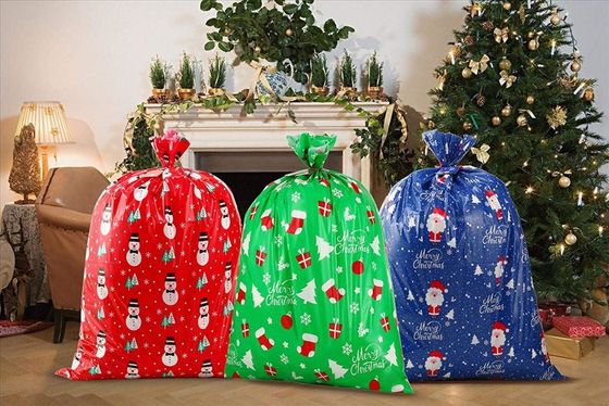 Il grande involucro di regalo di plastica insacca/sacchi del Babbo Natale con la carta e la corda di etichetta di nome